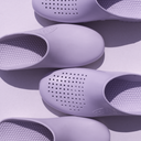 Purple clogs with textured soles on a light purple background