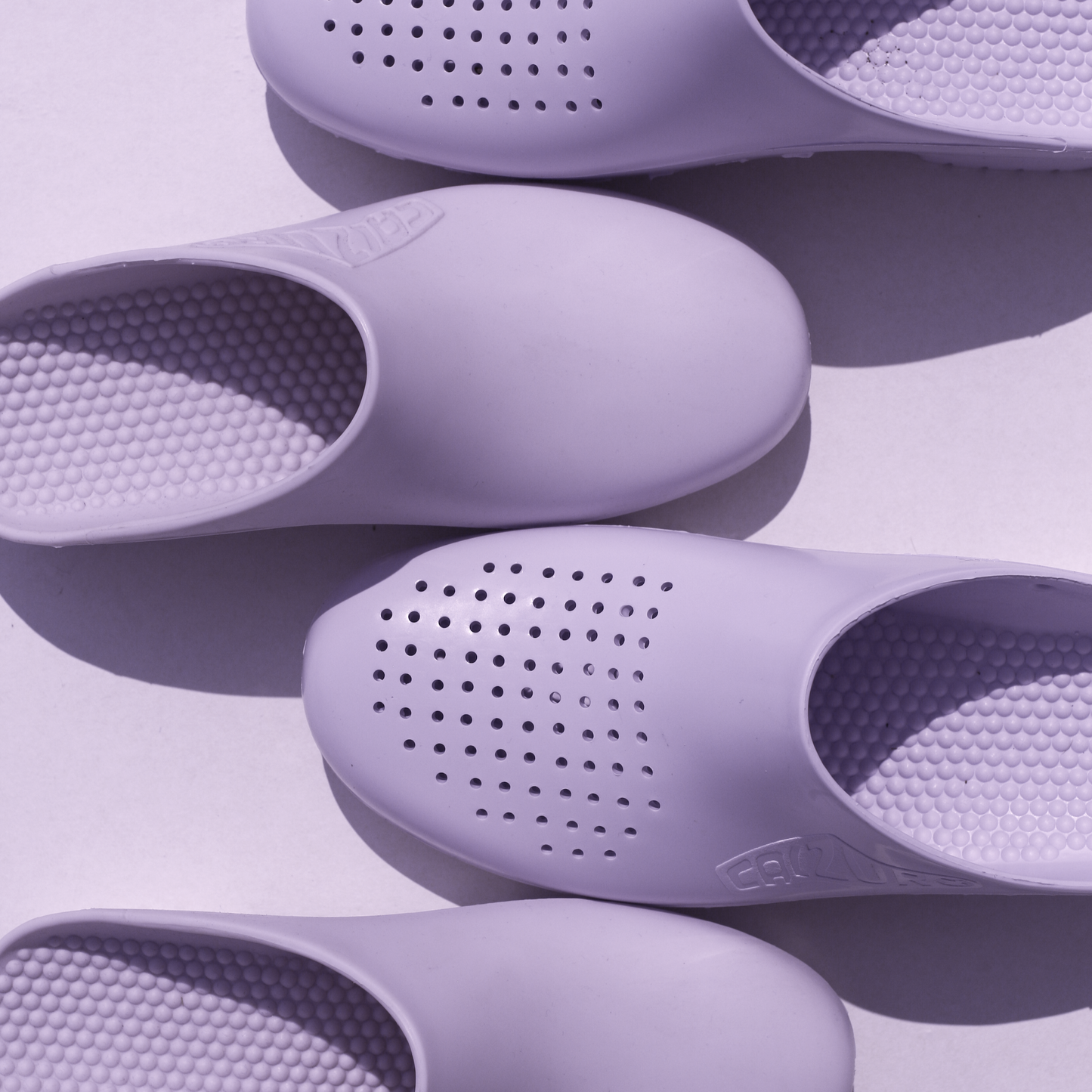 Purple clogs with textured soles on a light purple background