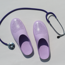 Purple clogs with a stethoscope on a light gray background